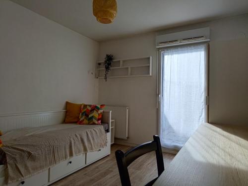 a bedroom with a bed and a window and a chair at Studio avec grande terrasse gare Sud in Nantes