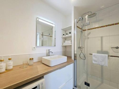 a white bathroom with a sink and a shower at La Pause Dorée d'Anne-Sophie in Bruz