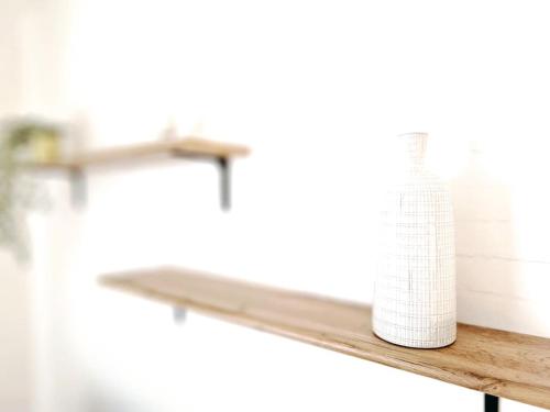 a wooden shelf with a white bottle on it at La Pause Dorée d'Anne-Sophie in Bruz