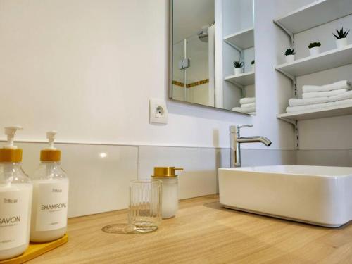 a bathroom counter with a sink and a mirror at La Pause Dorée d'Anne-Sophie in Bruz