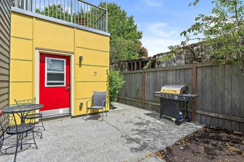 a yellow building with a red door and a grill at Pacific Trillium Studio, Wallingford 97 Walkscore in Seattle