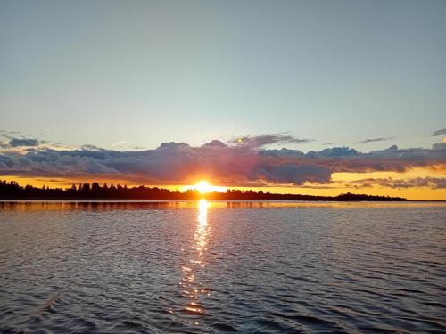 una puesta de sol sobre un cuerpo de agua en Romantiline ja privaatne talu Pädaste lahe ääres en Pädaste