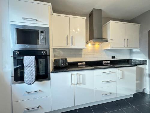 a kitchen with white cabinets and black appliances at Riverside House, North Shields Fish Quay in North Shields