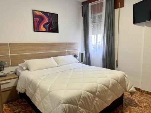 1 dormitorio con 1 cama blanca grande y TV en Apartamento San Agustín - Alojamientos El Duque, en Córdoba