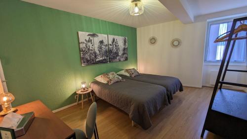 a green bedroom with a bed and a table at La Ferme des Denis in Chanos-Curson
