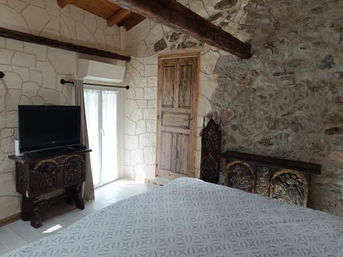 a bedroom with a bed and a tv and a stone wall at La petite tanière in Fontan
