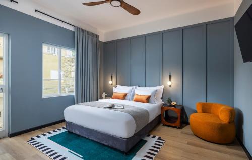 een slaapkamer met een bed en een oranje stoel bij Albi Florentin in Tel Aviv