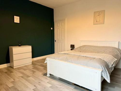 a bedroom with a white bed and a green wall at Sea View Retreat in Lingdale