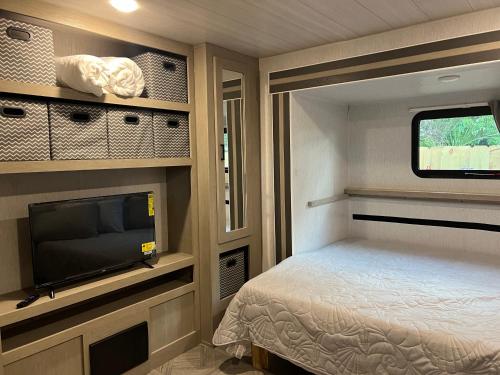 een kleine slaapkamer met een bed en een flatscreen-tv bij Homestead RV in Homestead