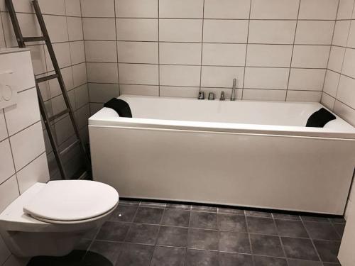 a bathroom with a white tub and a toilet at Familiebolig med nydelig utsikt in Trondheim