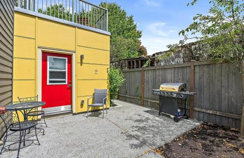 a yellow building with a red door and a grill at Salmonberry Studio in Wallingford - 97 Walkscore! in Seattle