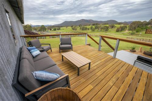 a porch with a couch and chairs on a deck at The Overflow Blue Mountains in Kanimbla