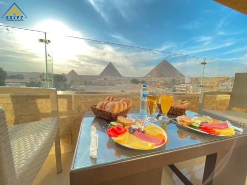 einen Tisch mit Speisen und Getränken auf einem Balkon mit Pyramiden in der Unterkunft Egypt Pyramids Inn in Kairo