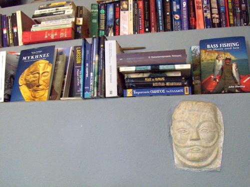 a book shelf with books and a mask on it at Anesis Hotel in Agios Ioannis Pelio