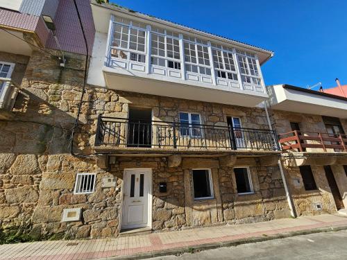 - un bâtiment en pierre avec un balcon et une porte blanche dans l'établissement Carmen House - Laxe - Costa da Morte, à Laxe
