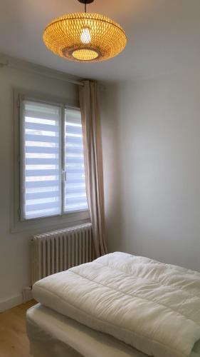 - une chambre avec un lit, une fenêtre et un lustre dans l'établissement La Boissière, à Avrillé