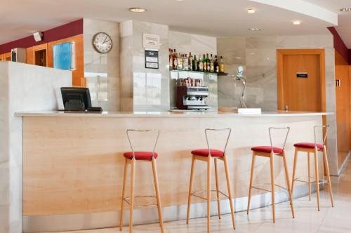 a bar with four red stools at a counter at Hotel Holiday Inn Express Madrid-Rivas by IHG in Rivas-Vaciamadrid