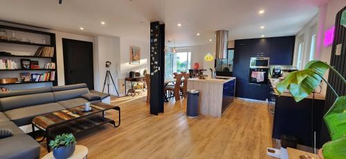un salon avec un canapé et une table et une cuisine dans l'établissement Logement 100m² industriel avec jardin et terrasse, à Brumath