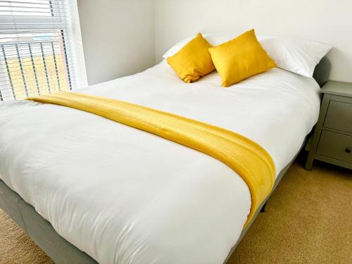 a bed with white sheets and yellow pillows at Modern 2-Bedroom Apartment in Bristol