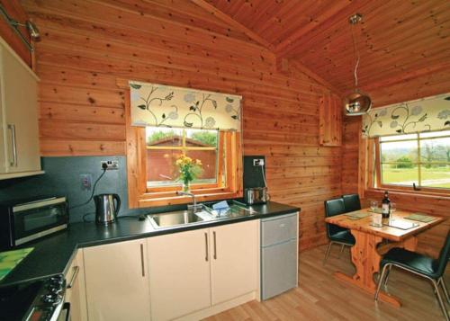 a kitchen with a sink and a table in a cabin at Spindlewood Lodges in North Wootton
