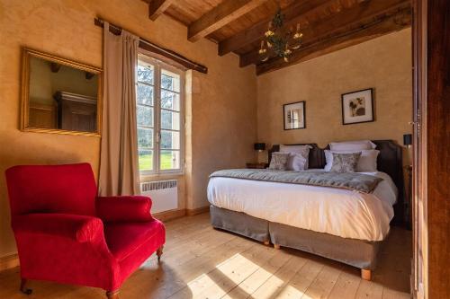 een slaapkamer met een bed en een rode stoel bij le Domaine du Trouiller in Cendrieux