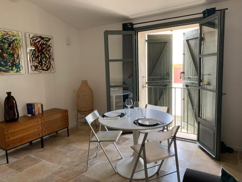 une salle à manger avec une table et des chaises blanches dans l'établissement LE BLANC CAMARGUE - STUDIO DANS LES REMPARTS 45m2 AVEC CLIM, à Aigues-Mortes