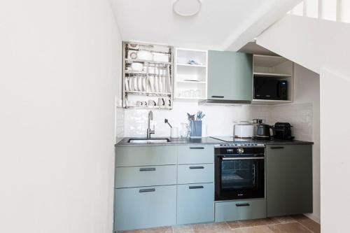 une cuisine avec des armoires blanches et un four à plaques de cuisson dans l'établissement LE BLANC CAMARGUE - STUDIO DANS LES REMPARTS 45m2 AVEC CLIM, à Aigues-Mortes