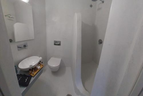 a white bathroom with a toilet and a sink at East Wind Perissa in Perissa