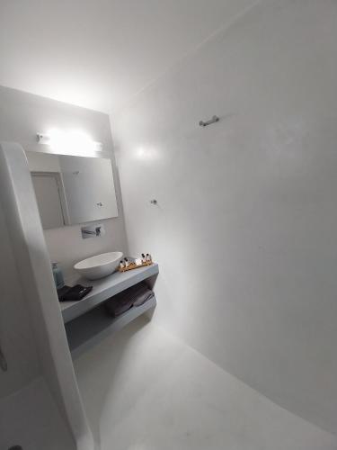 a white bathroom with a sink and a counter at East Wind Perissa in Perissa