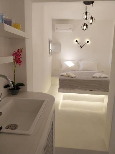 a white bedroom with a bed and a sink at East Wind Perissa in Perissa