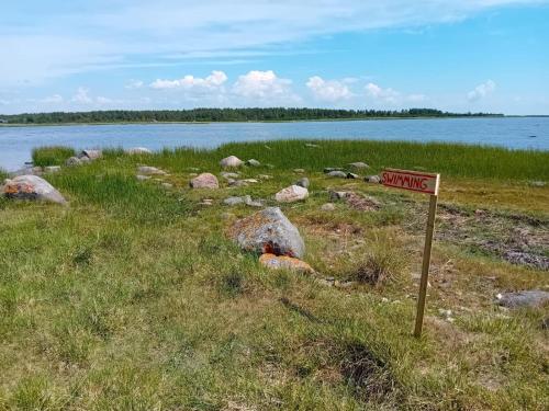 a sign in the grass next to a body of water at Romantiline saunamaja Pädaste lahe ääres in Pädaste