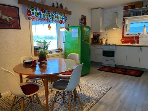 uma cozinha com uma mesa e um frigorífico verde em Nice little house right by the sea, stunning view! em Renså