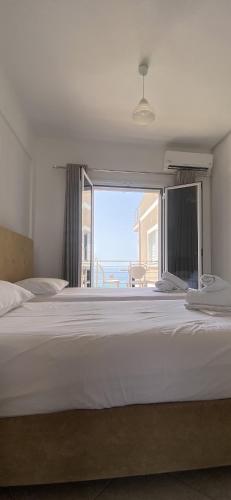 a bedroom with a large white bed and a large window at VANGJELIS HOTEL in Himare