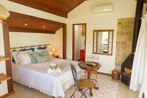 um quarto com uma cama e uma mesa num quarto em Pousada das Bromélias em Ipiabas