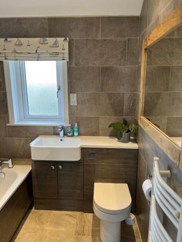 a bathroom with a sink and a toilet and a window at 5 Beechcroft Cottage - Seahouses Northumberland in Seahouses