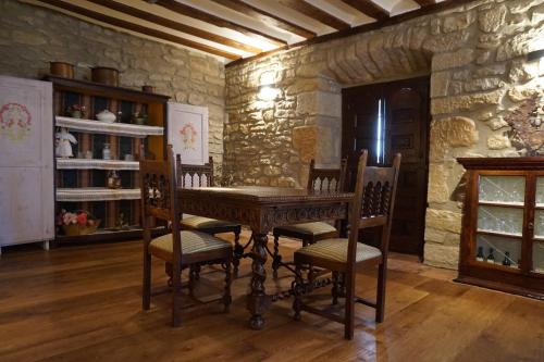 a table and chairs in a room with a stone wall at Arganzón Plaza in La Puebla de Arganzón
