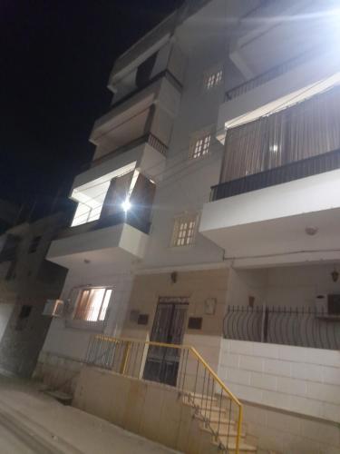 a large white building with a staircase in front of it at Luxorya hotel apartment in Nag` Naqsha
