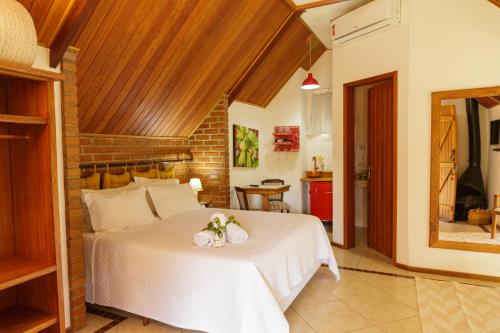 a bedroom with a large white bed in a room at Pousada das Bromélias in Ipiabas