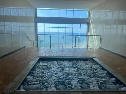 a hot tub in a room with a large window at Sunset Beach View Holiday Homes in Ajman 