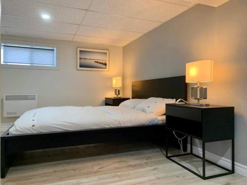 1 dormitorio con 1 cama grande y escritorio con lámpara en Ting’s Place - Luxury suite, en Campbellton