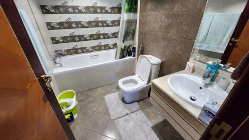 a bathroom with a toilet and a tub and a sink at Sunset Beach View Holiday Homes in Ajman 