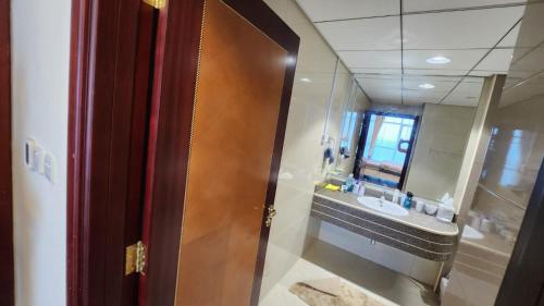 a bathroom with a sink and a wooden door at Sunset Beach View Holiday Homes in Ajman 