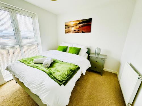 a bedroom with a bed with white sheets and green pillows at Modern 2-Bedroom Apartment in Bristol