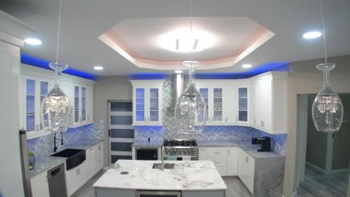 a kitchen with white cabinets and blue walls and chandeliers at Golden Pear Villa-CR in Confer