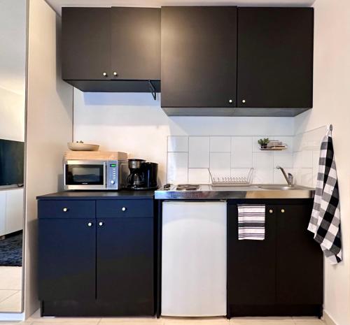- une cuisine avec des placards noirs et blancs et un four micro-ondes dans l'établissement Studio cosy à 15 min de Bastille, à Alfortville