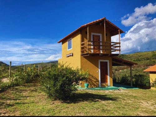 een klein huis met een balkon erboven bij Chalé Nova Aurora in São Thomé das Letras