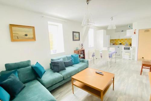 un salon avec un canapé bleu et une table dans l'établissement Gîte du Moulin - Appartement plein centre ville - spacieux 2p - 1er etage maison de pécheur à 100m de la plage, au Crotoy