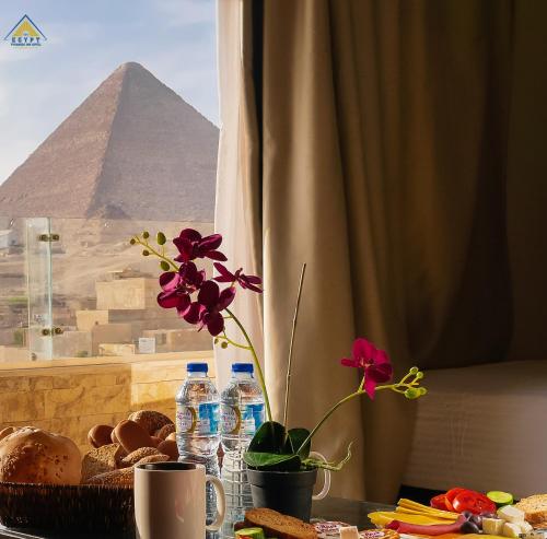 a table with flowers and a view of the pyramids at Egypt Pyramids Inn in Cairo
