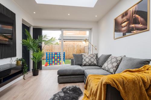 a living room with a gray couch and a large window at Dazzling & Modern 4bd - Coop LIVE - Etihad - Parking in Manchester