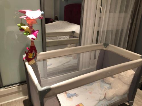 ein Babybett in einem Zimmer mit Spiegel in der Unterkunft ChezClervie Nanterre City, Close To Paris La Défense U Arena in Nanterre